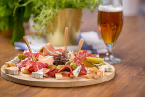 SnackPlatterWithDifferentCheesesParmaHamSalamiSausageAnd | Niemann Harvest Market charcuterie plate with beer